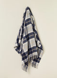 Plaid blanket draped over a chair on a beige background