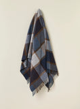 Plaid blanket with blue, brown, and gray pattern on a beige background